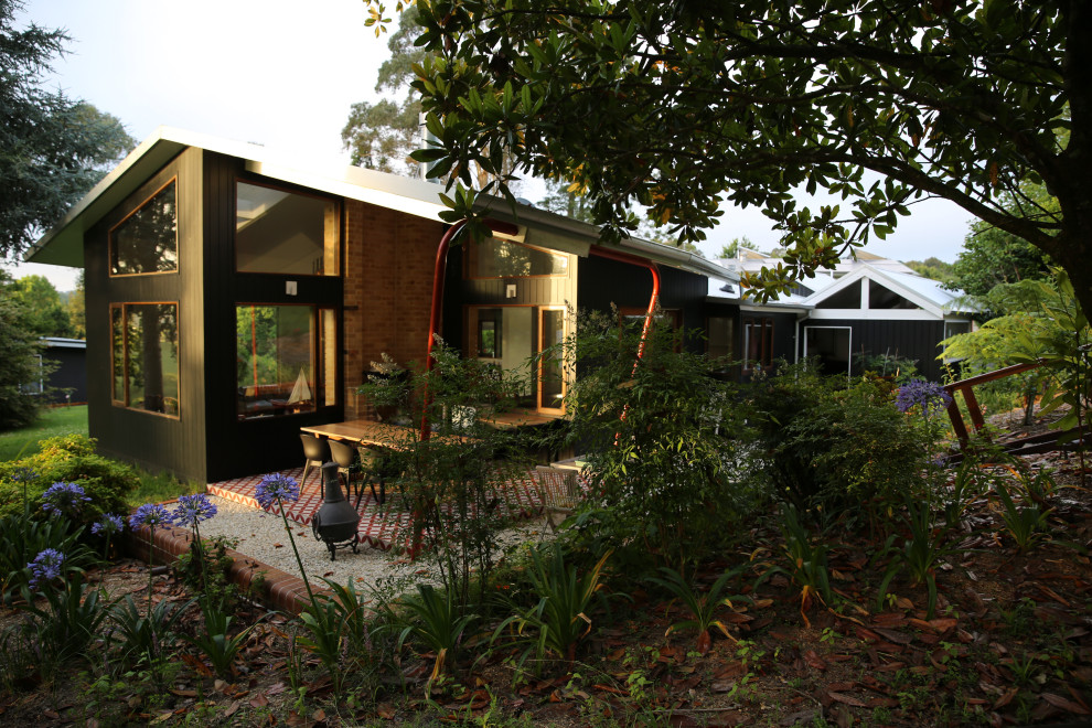 Imagen de patio retro de tamaño medio en patio y anexo de casas con chimenea y suelo de baldosas