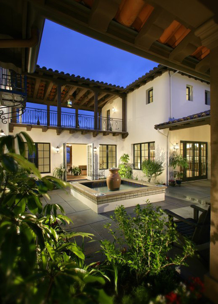 Пример оригинального дизайна: двор на внутреннем дворе в средиземноморском стиле с фонтаном, покрытием из плитки и навесом