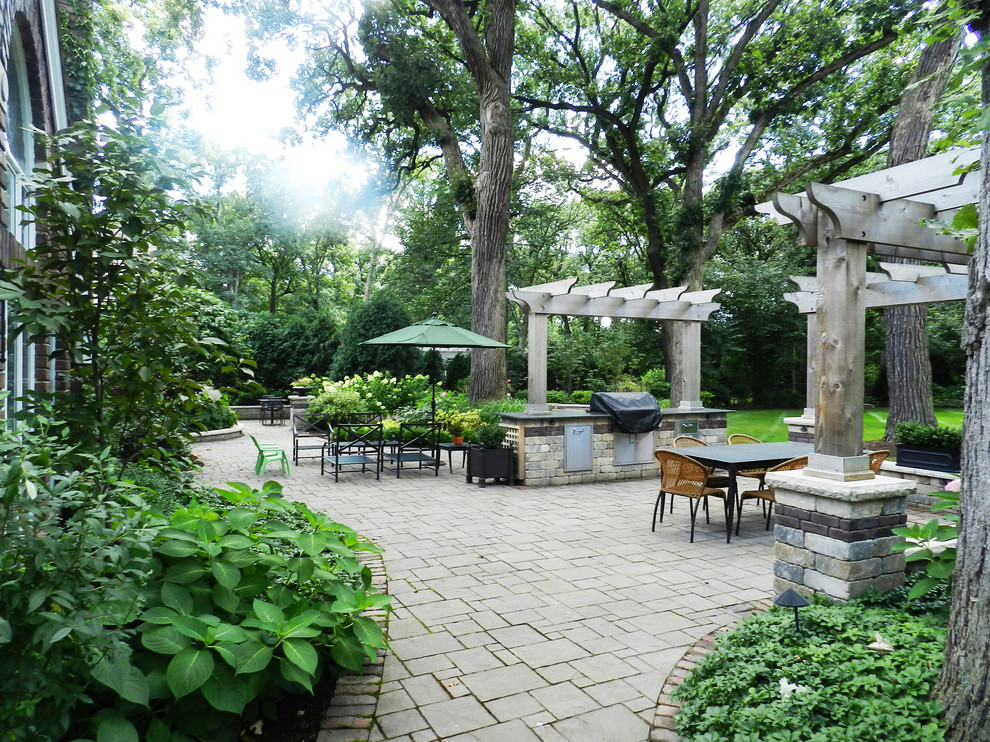 Design ideas for a medium sized classic back patio in Chicago with brick paving, a pergola and an outdoor kitchen.