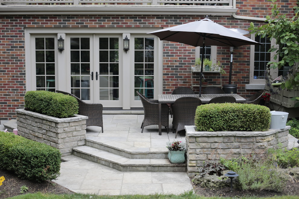 Example of a mid-sized classic backyard stone patio design in Toronto