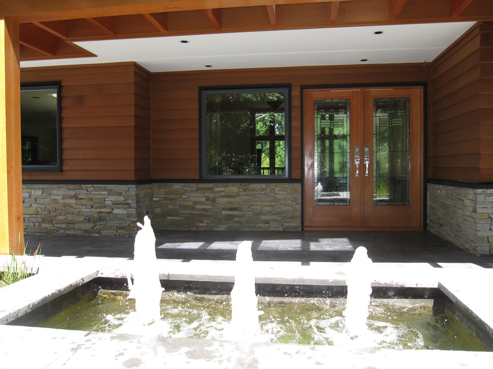 Esempio di un patio o portico american style di medie dimensioni e davanti casa con fontane, lastre di cemento e un tetto a sbalzo