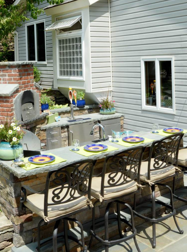 Exemple d'une terrasse arrière chic avec des pavés en pierre naturelle et une cuisine d'été.