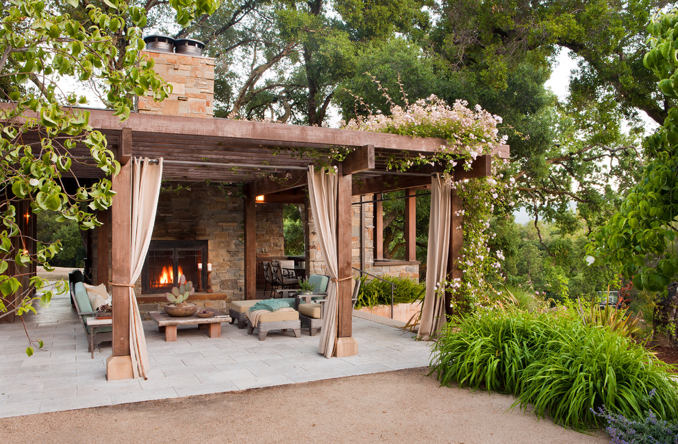 Example of a mid-sized tuscan backyard stone patio design in San Francisco with a pergola and a fireplace