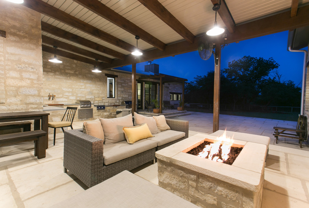 Inspiration for a rural patio in Austin with a fire feature, natural stone paving and an awning.