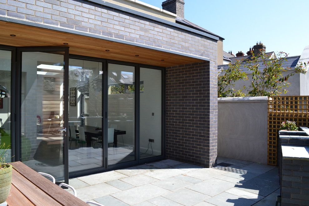 Idee per un patio o portico moderno di medie dimensioni e dietro casa con un tetto a sbalzo e pavimentazioni in pietra naturale