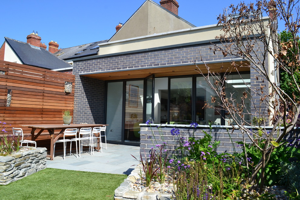 Immagine di un patio o portico moderno di medie dimensioni e dietro casa con un tetto a sbalzo e pavimentazioni in pietra naturale