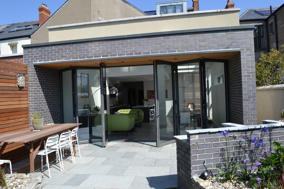 Ispirazione per un patio o portico moderno di medie dimensioni e dietro casa con un tetto a sbalzo e pavimentazioni in pietra naturale