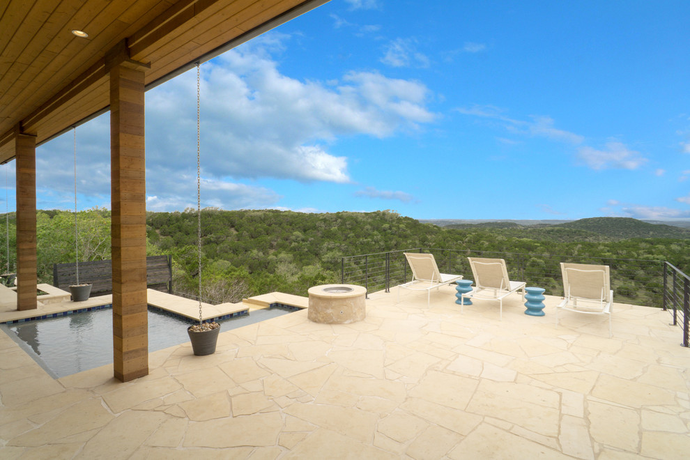 Design ideas for a large contemporary back patio in Austin with a fire feature, natural stone paving and a roof extension.
