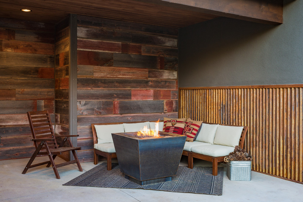 Design ideas for a small rustic back patio in Denver with a fire feature, concrete slabs and a roof extension.