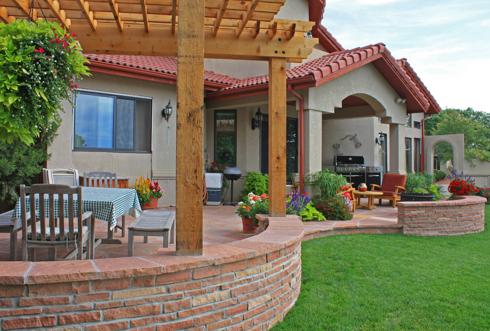 This is an example of a medium sized traditional back patio in Denver with a potted garden, natural stone paving and a pergola.