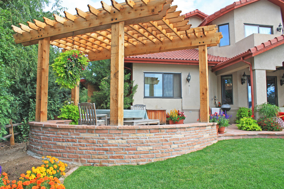 Ispirazione per un patio o portico american style di medie dimensioni e dietro casa con un giardino in vaso, pavimentazioni in pietra naturale e una pergola