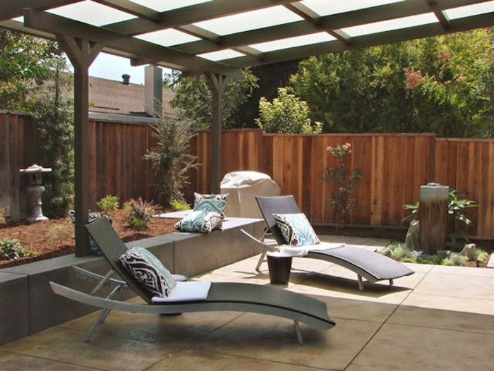 Imagen de patio contemporáneo de tamaño medio en patio trasero con fuente, suelo de baldosas y pérgola