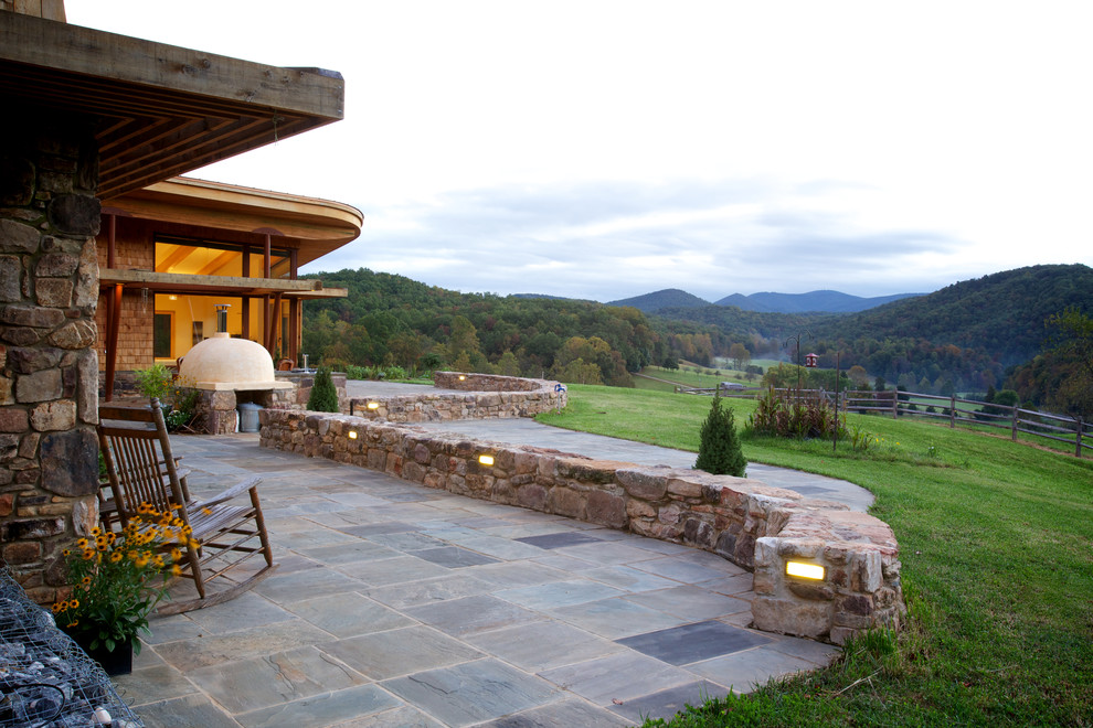 Example of a mountain style backyard stone patio design in Portland Maine with no cover and a fire pit