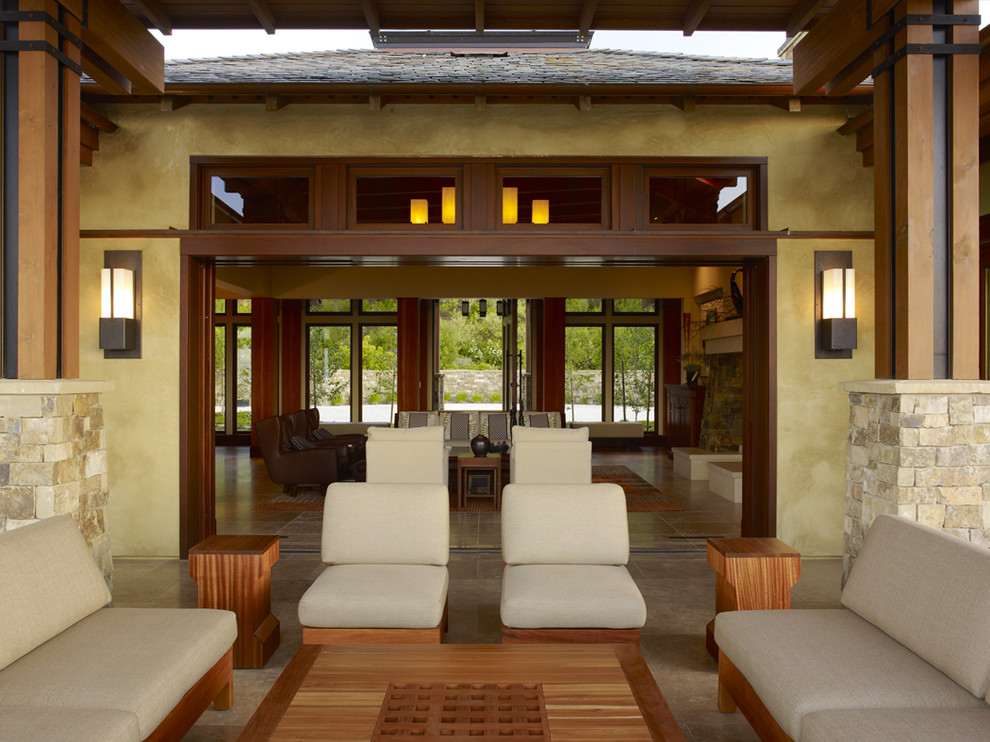 Inspiration pour une grande terrasse arrière design avec une extension de toiture et des pavés en pierre naturelle.