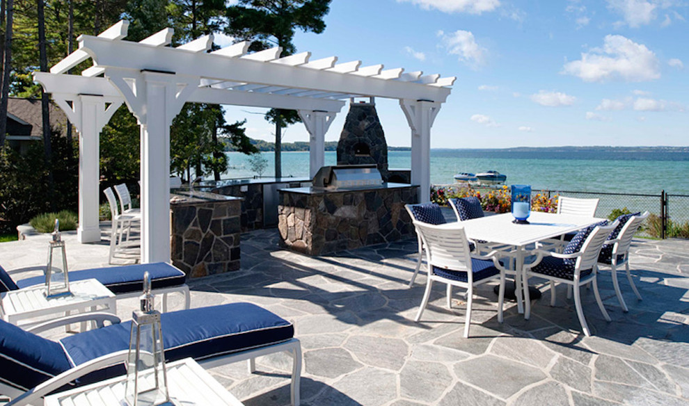 Inspiration pour une grande terrasse arrière marine avec une cuisine d'été, des pavés en pierre naturelle et une pergola.