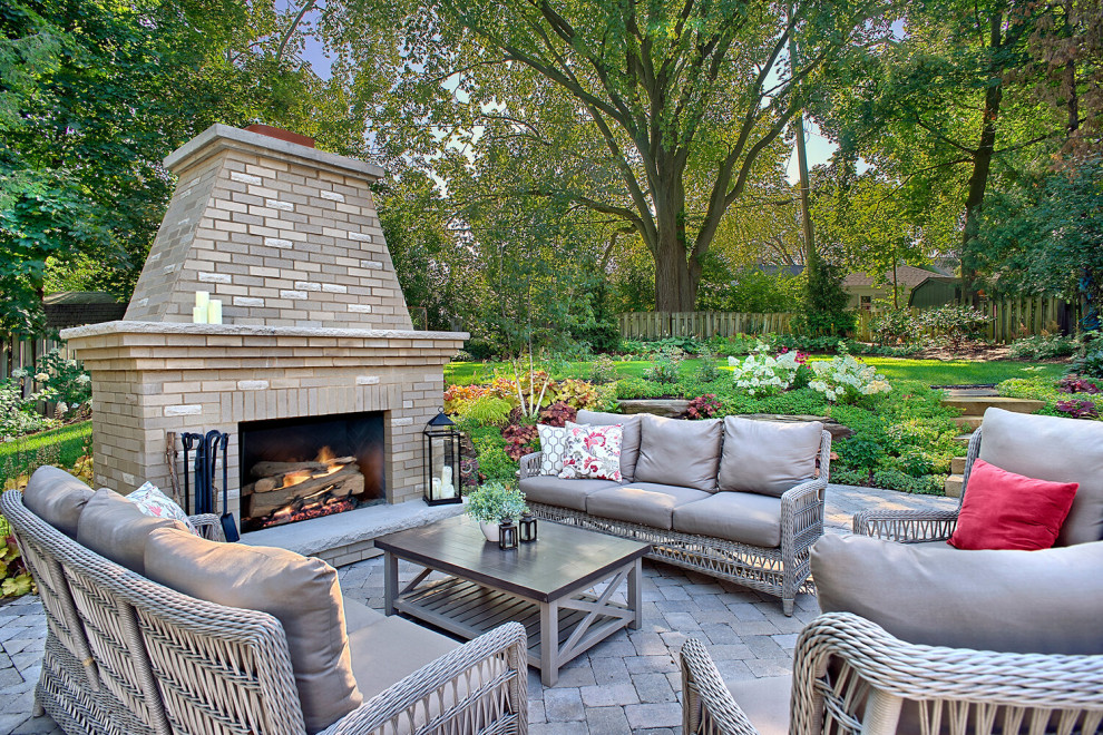 Modelo de patio clásico extra grande en patio trasero con chimenea y adoquines de ladrillo