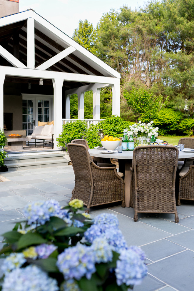 Foto di un ampio patio o portico costiero dietro casa con un giardino in vaso, pavimentazioni in pietra naturale e un tetto a sbalzo