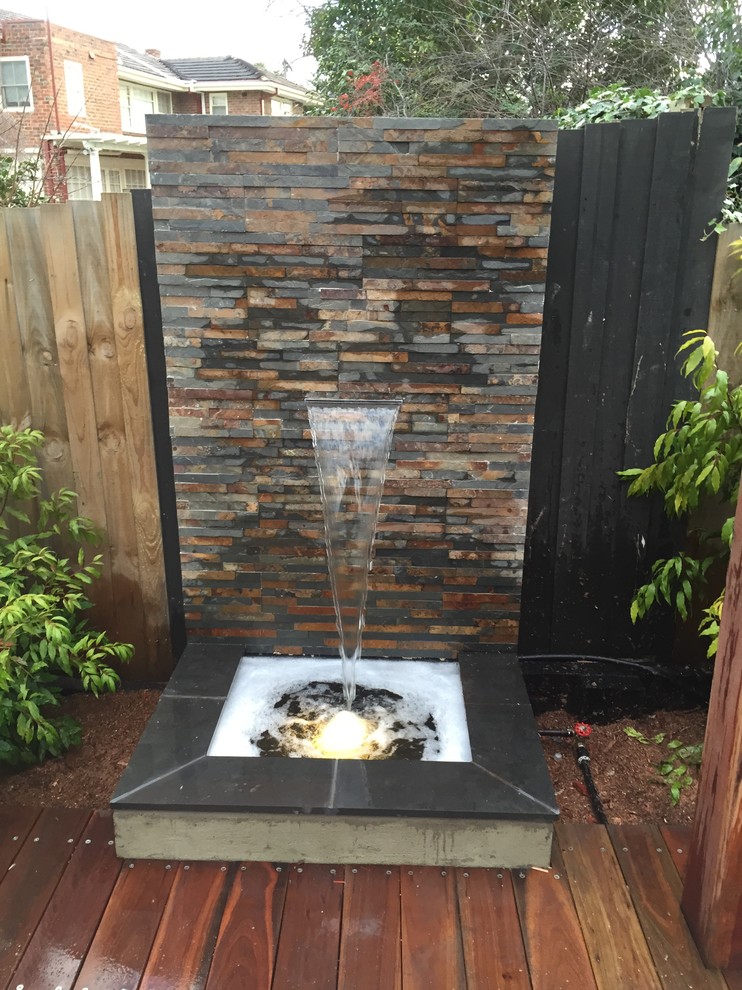 Example of a large trendy backyard patio fountain design in Melbourne with decking and no cover