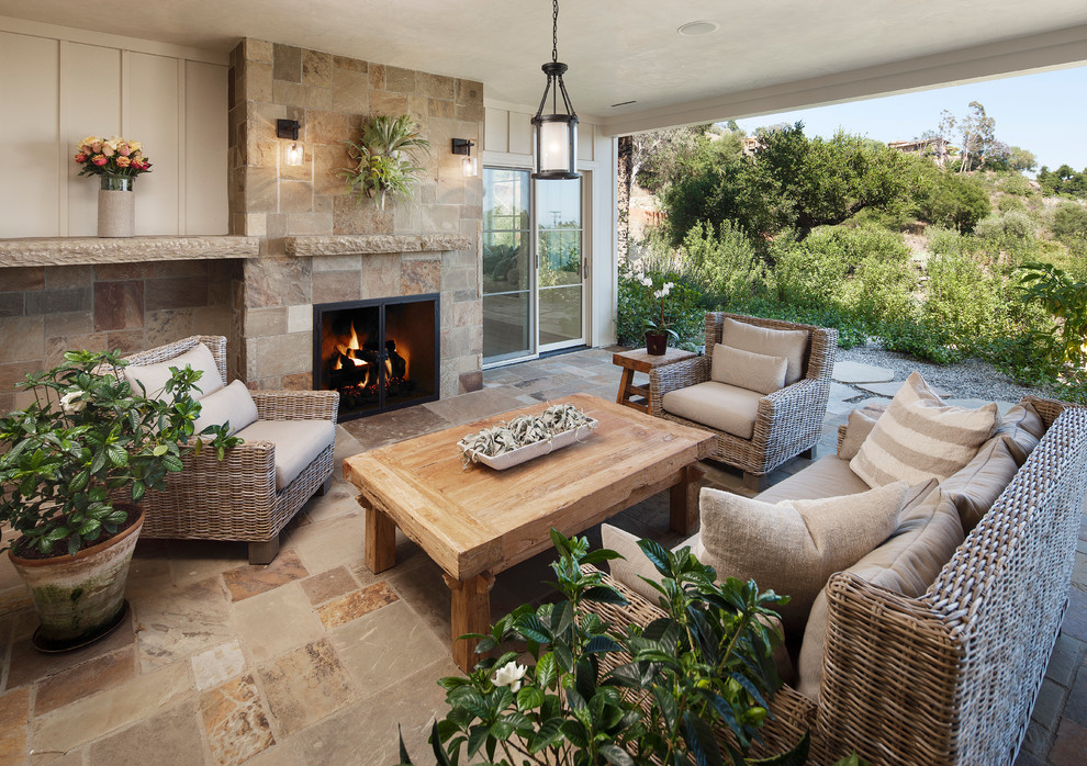 Idée de décoration pour une terrasse arrière tradition de taille moyenne avec un foyer extérieur, une extension de toiture et des pavés en pierre naturelle.