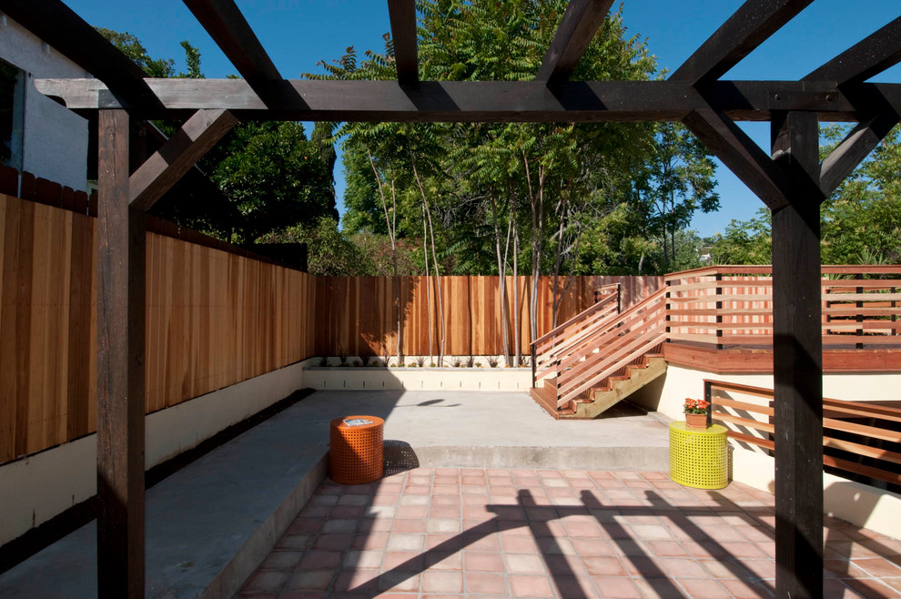 Immagine di un patio o portico mediterraneo di medie dimensioni e dietro casa con una pergola e piastrelle