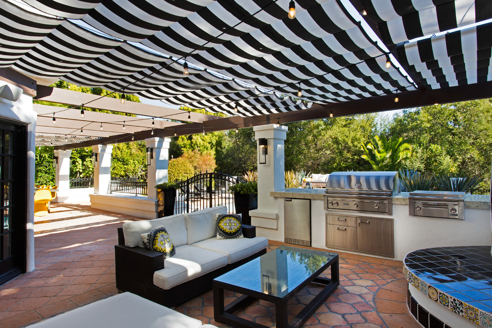 Imagen de patio mediterráneo grande en patio trasero con cocina exterior, toldo y suelo de baldosas