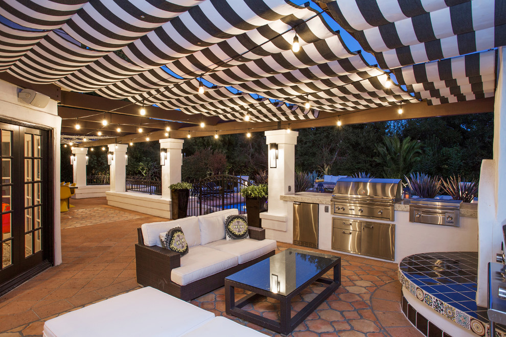 Large mediterranean back patio in Los Angeles with an outdoor kitchen, an awning and tiled flooring.