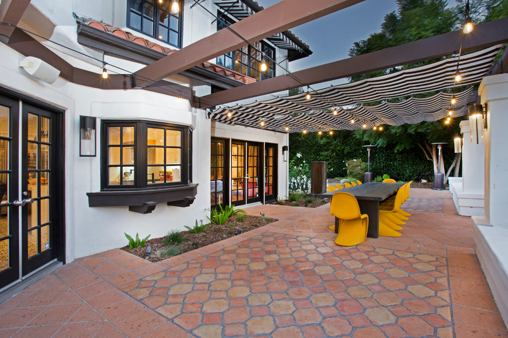 Immagine di un patio o portico boho chic di medie dimensioni e nel cortile laterale con piastrelle e un parasole