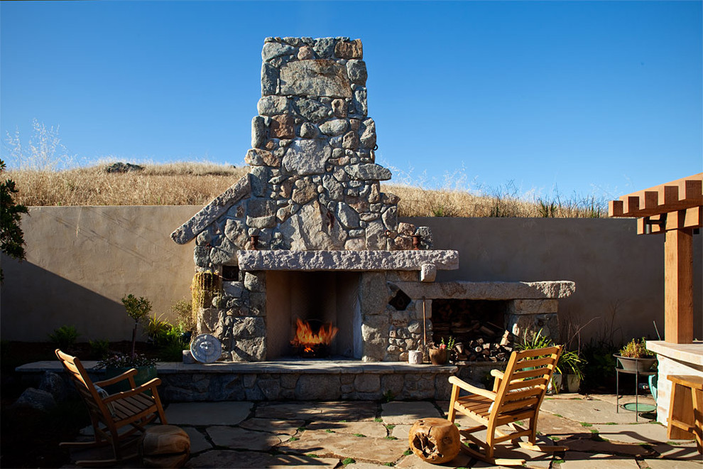 Exemple d'une terrasse éclectique avec des pavés en pierre naturelle et une pergola.