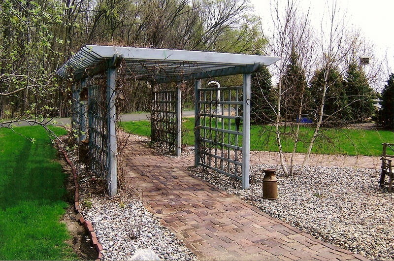 Modelo de patio ecléctico pequeño en patio trasero con adoquines de ladrillo y pérgola