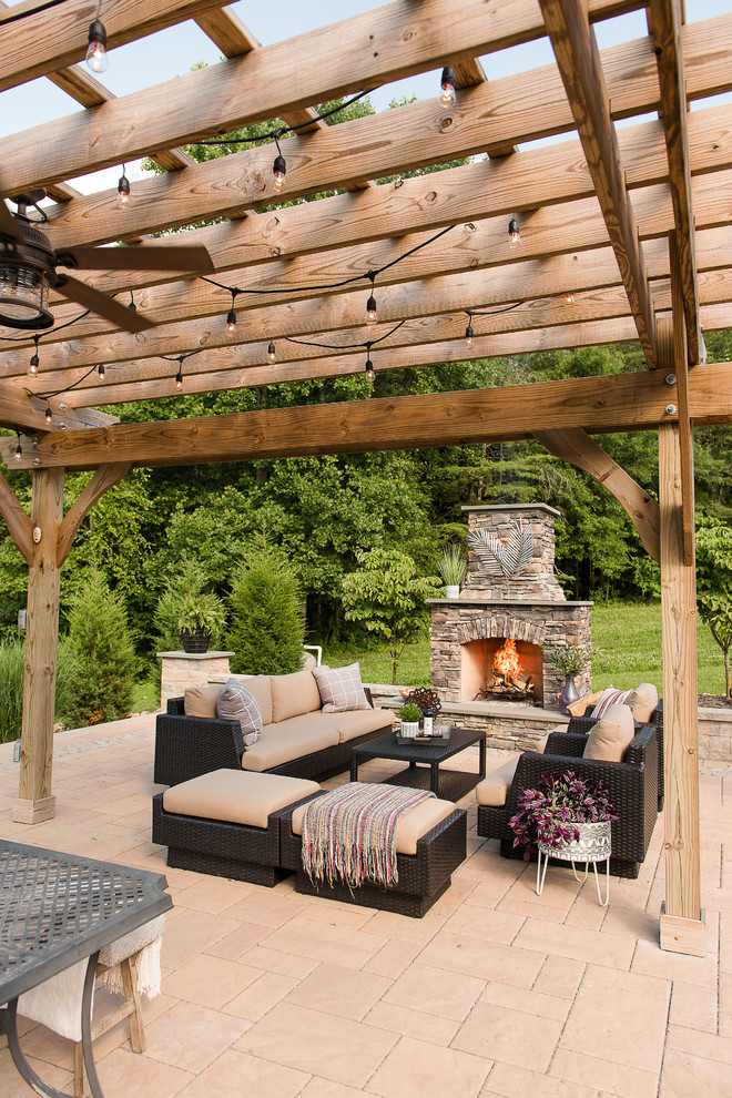 Idée de décoration pour une grande terrasse arrière chalet avec une cheminée, des pavés en béton et une pergola.