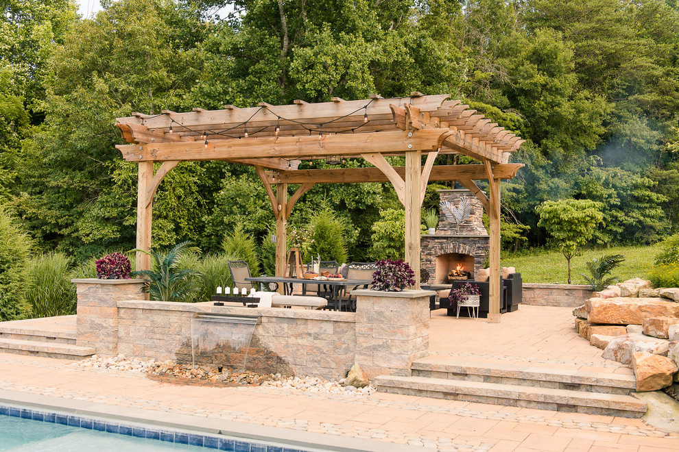 Example of a large mountain style backyard concrete paver patio design in Richmond with a fireplace and a pergola