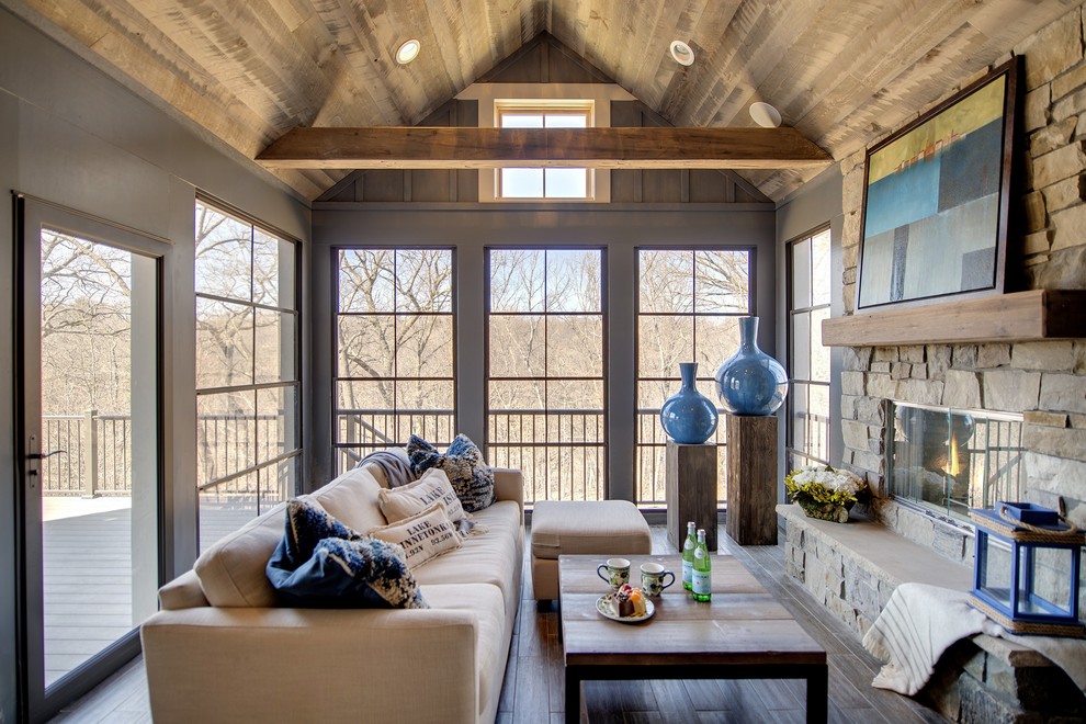 Cette photo montre une terrasse en bois arrière chic de taille moyenne avec une extension de toiture et un foyer extérieur.
