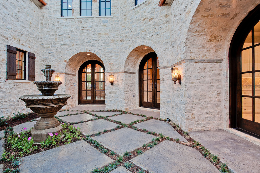 Inspiration for a large mediterranean courtyard patio in Dallas with a water feature, concrete slabs and no cover.