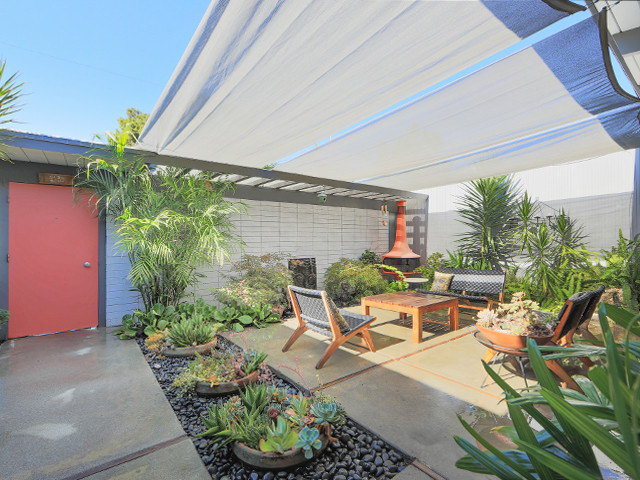 Cette image montre une terrasse vintage de taille moyenne avec un foyer extérieur, une cour, des pavés en béton et un auvent.