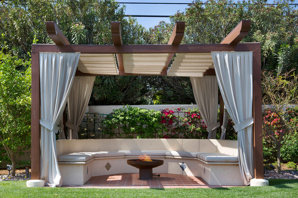 This is an example of a classic back patio in Los Angeles with a fire feature, tiled flooring and a pergola.