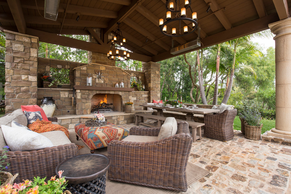 Modelo de patio mediterráneo grande en patio trasero con adoquines de piedra natural, cenador y chimenea