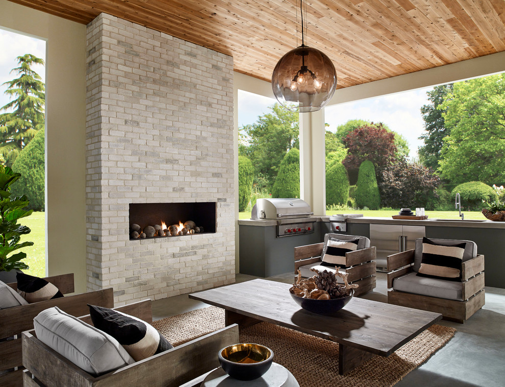 Aménagement d'une grande terrasse arrière classique avec une cuisine d'été, une dalle de béton et une extension de toiture.