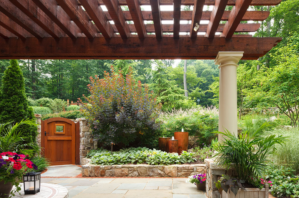 Imagen de patio clásico de tamaño medio en patio trasero con adoquines de piedra natural