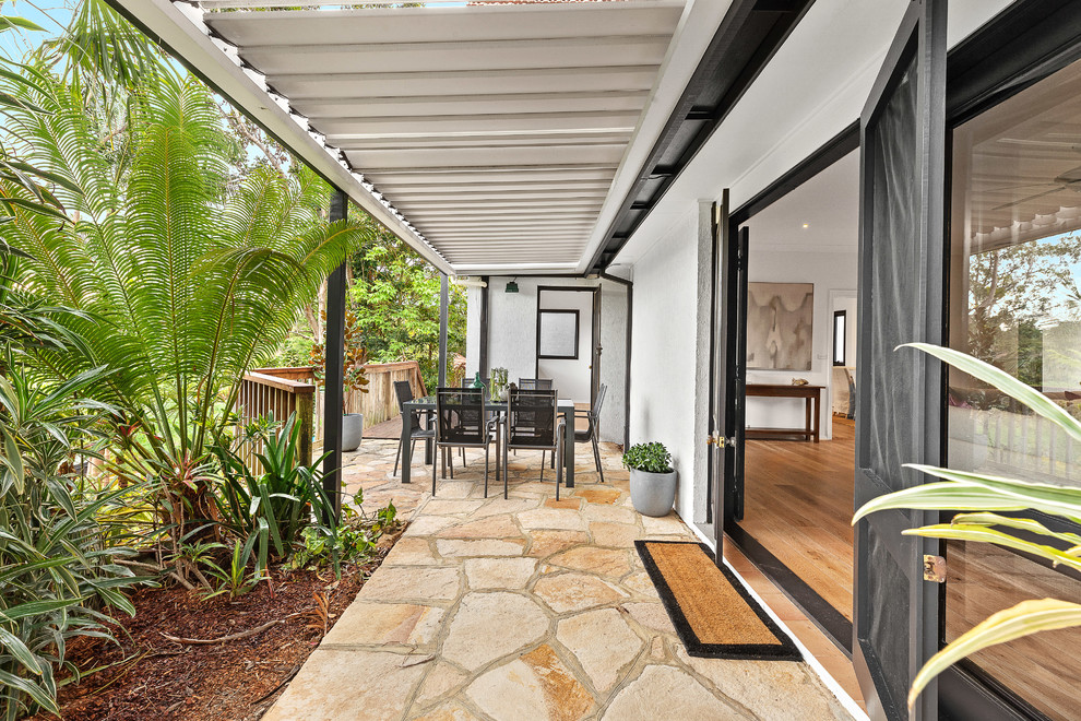 Immagine di un patio o portico classico di medie dimensioni e dietro casa con pavimentazioni in pietra naturale e un parasole