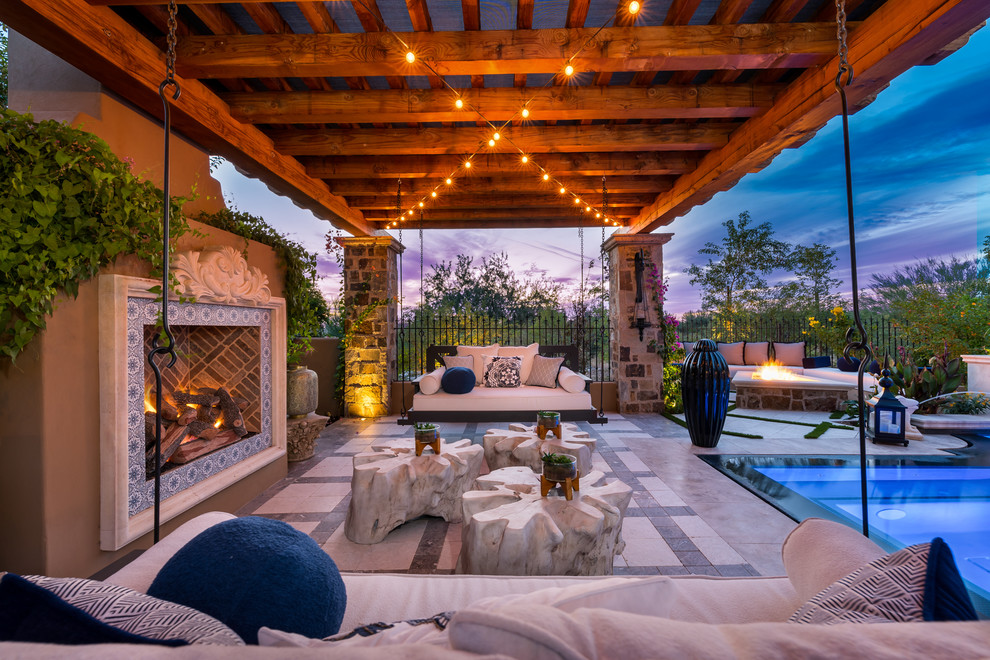 Immagine di un ampio patio o portico minimalista dietro casa con un focolare, pavimentazioni in pietra naturale e un tetto a sbalzo