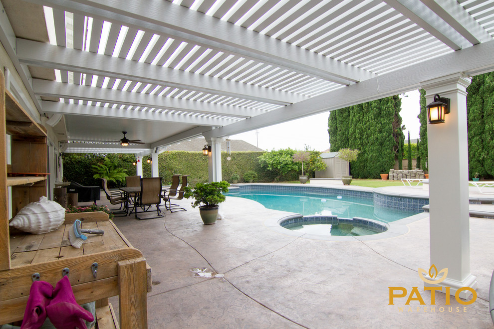 Example of a classic backyard stamped concrete patio design in Orange County with a pergola