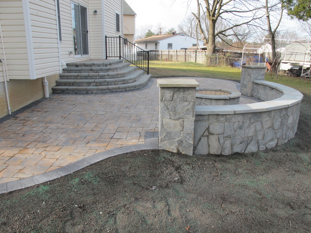 Example of a mid-sized classic backyard stone patio design in Baltimore with a fire pit and no cover