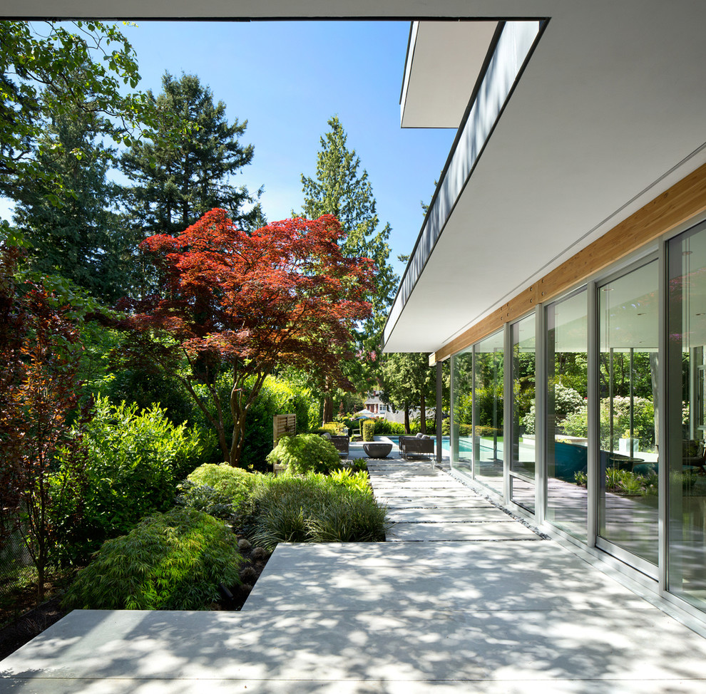 На фото: большой двор на боковом дворе в современном стиле с покрытием из бетонных плит и козырьком с