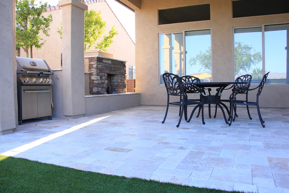 Photo of a medium sized mediterranean back patio in Phoenix with a fire feature, natural stone paving and a roof extension.