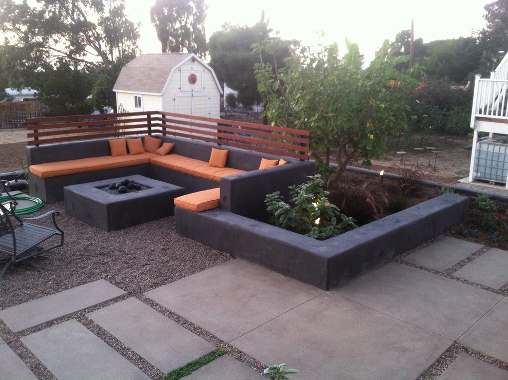 This is an example of a medium sized contemporary back patio in San Diego with a fire feature, concrete slabs and no cover.