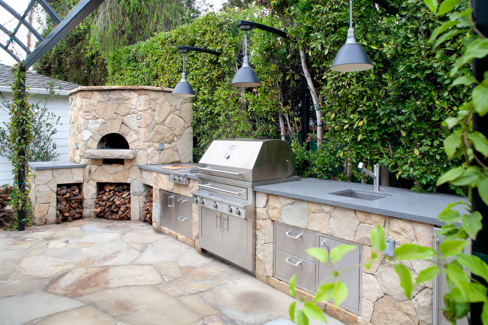 Réalisation d'une terrasse arrière design de taille moyenne avec une cuisine d'été, des pavés en pierre naturelle et une pergola.