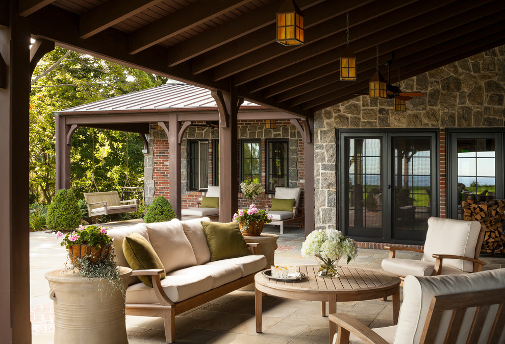 Immagine di un grande patio o portico stile americano dietro casa con pavimentazioni in pietra naturale e un tetto a sbalzo
