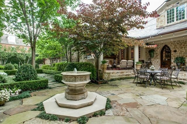 This is an example of a classic back patio in Dallas with a water feature, natural stone paving and a roof extension.