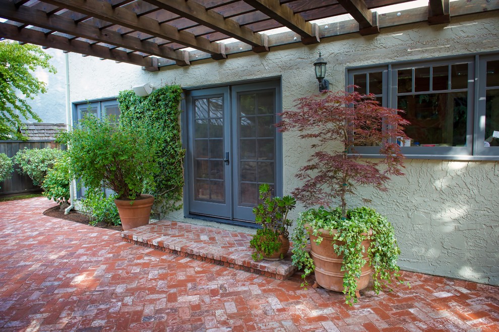 Ispirazione per un patio o portico chic di medie dimensioni e dietro casa con un giardino in vaso, pavimentazioni in mattoni e una pergola