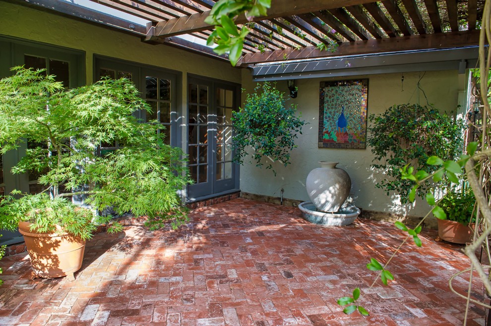 Ispirazione per un patio o portico tradizionale di medie dimensioni e dietro casa con un giardino in vaso, pavimentazioni in mattoni e una pergola